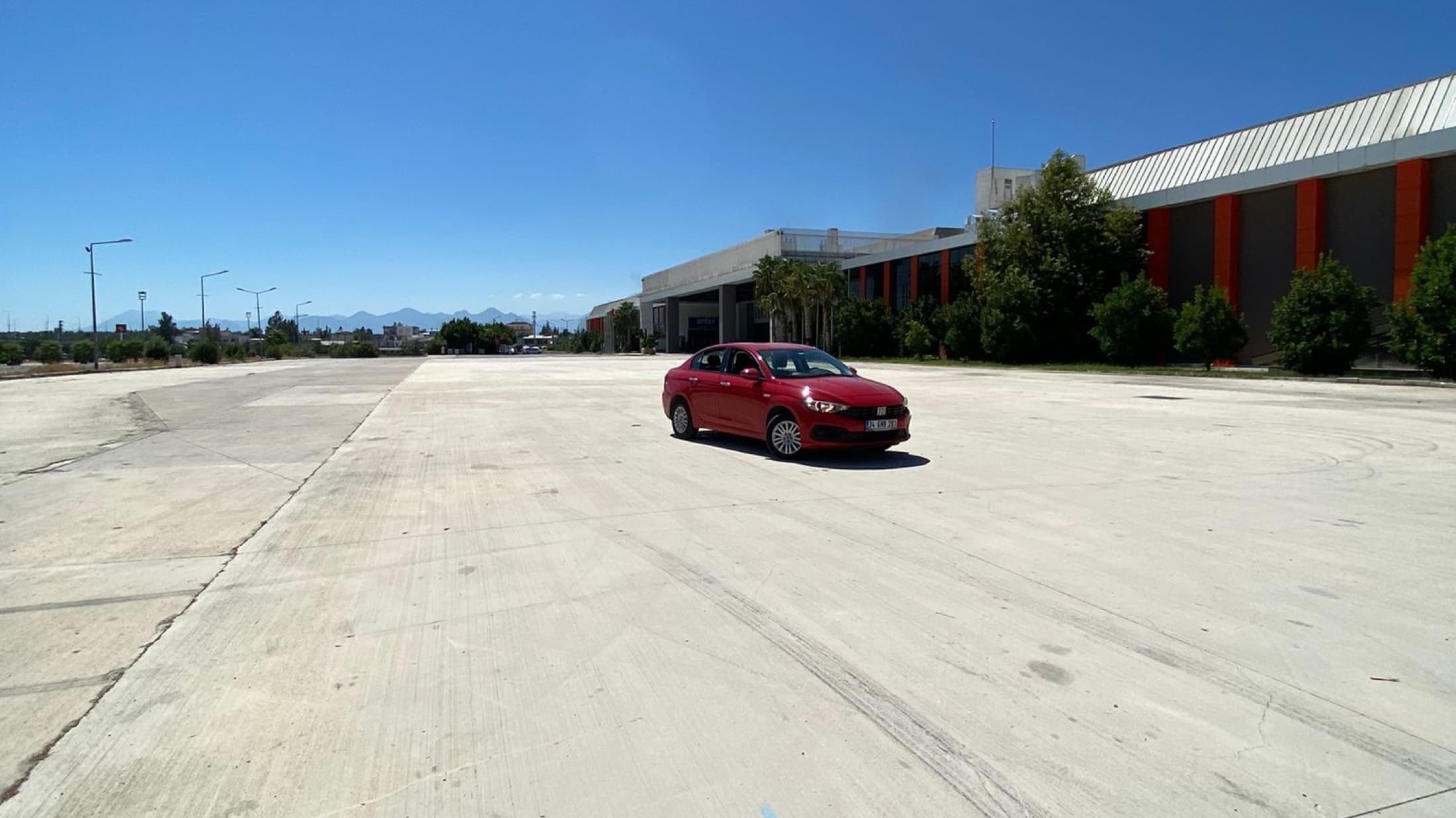 Antalya Aksu'da beton alanda park etmiş kırmızı Fiat Egea